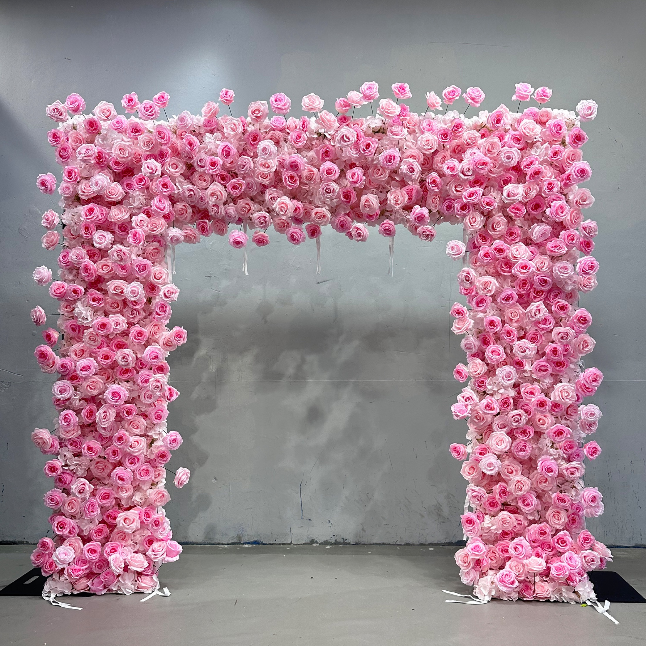 Square faux-flower arch covered in blush and bright pink roses