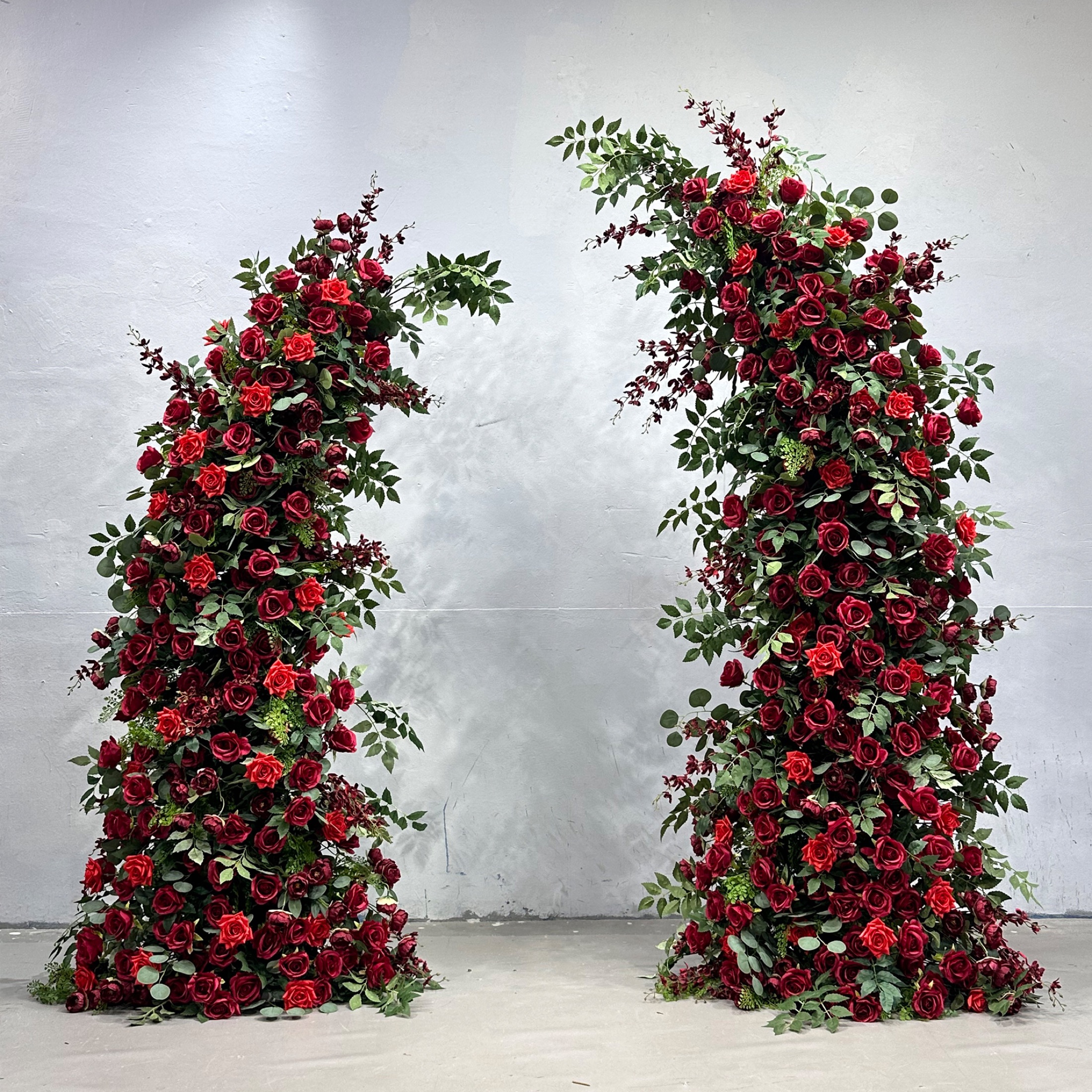 Horn-shaped faux-flower arch with deep burgundy and red roses