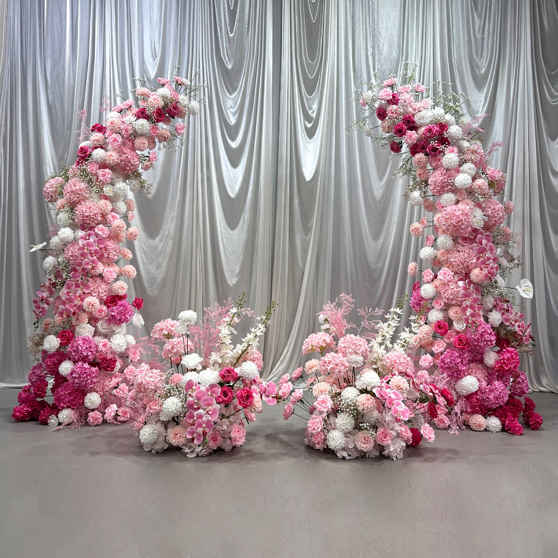 U-shaped pink faux-flower arch with hydrangeas, roses and ground florals