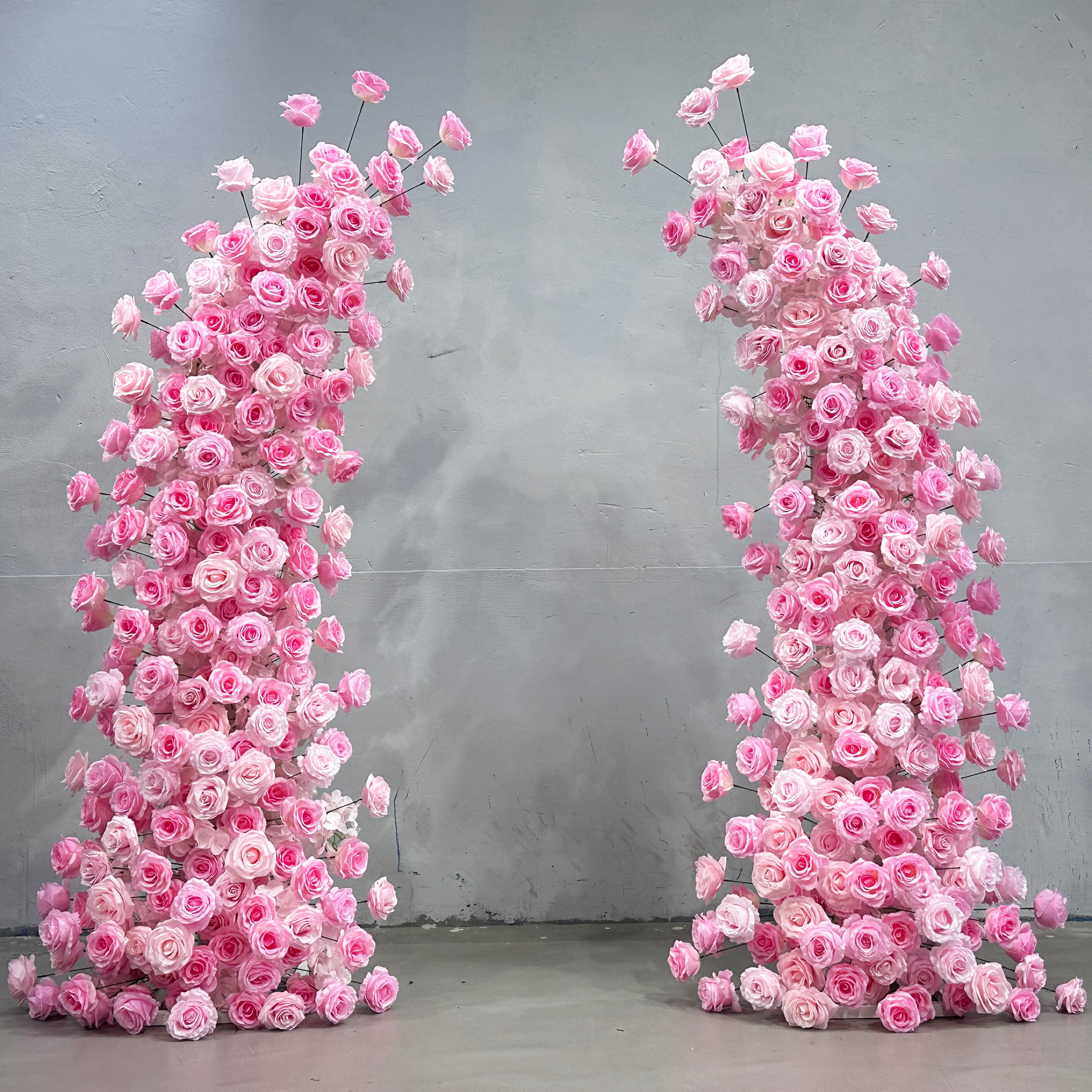 Horn-shaped faux-flower arch covered in soft and bright pink roses