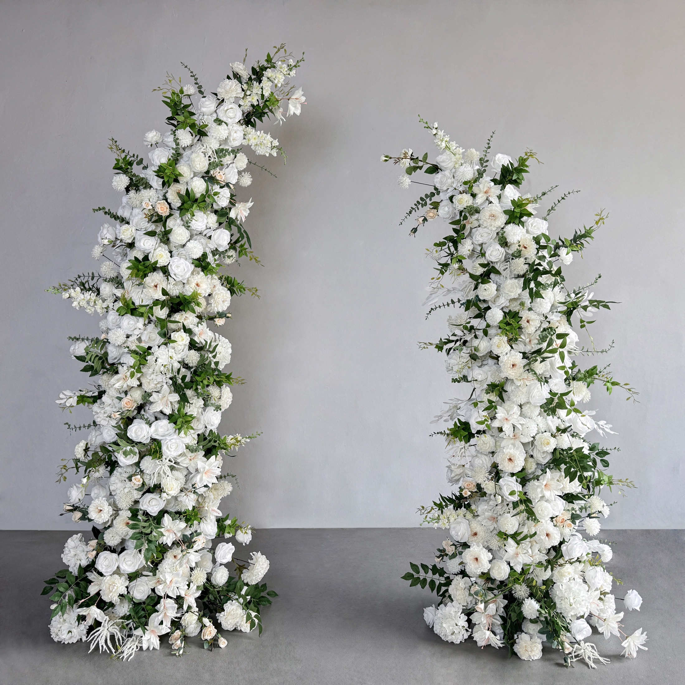 Horn-shaped faux-flower arch with layered white flowers and greenery