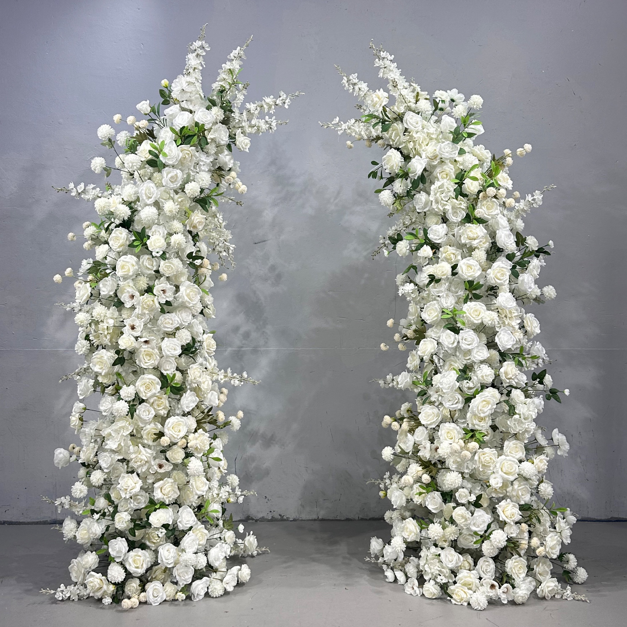 Horn-shaped faux-flower arch filled with white roses and delicate greenery