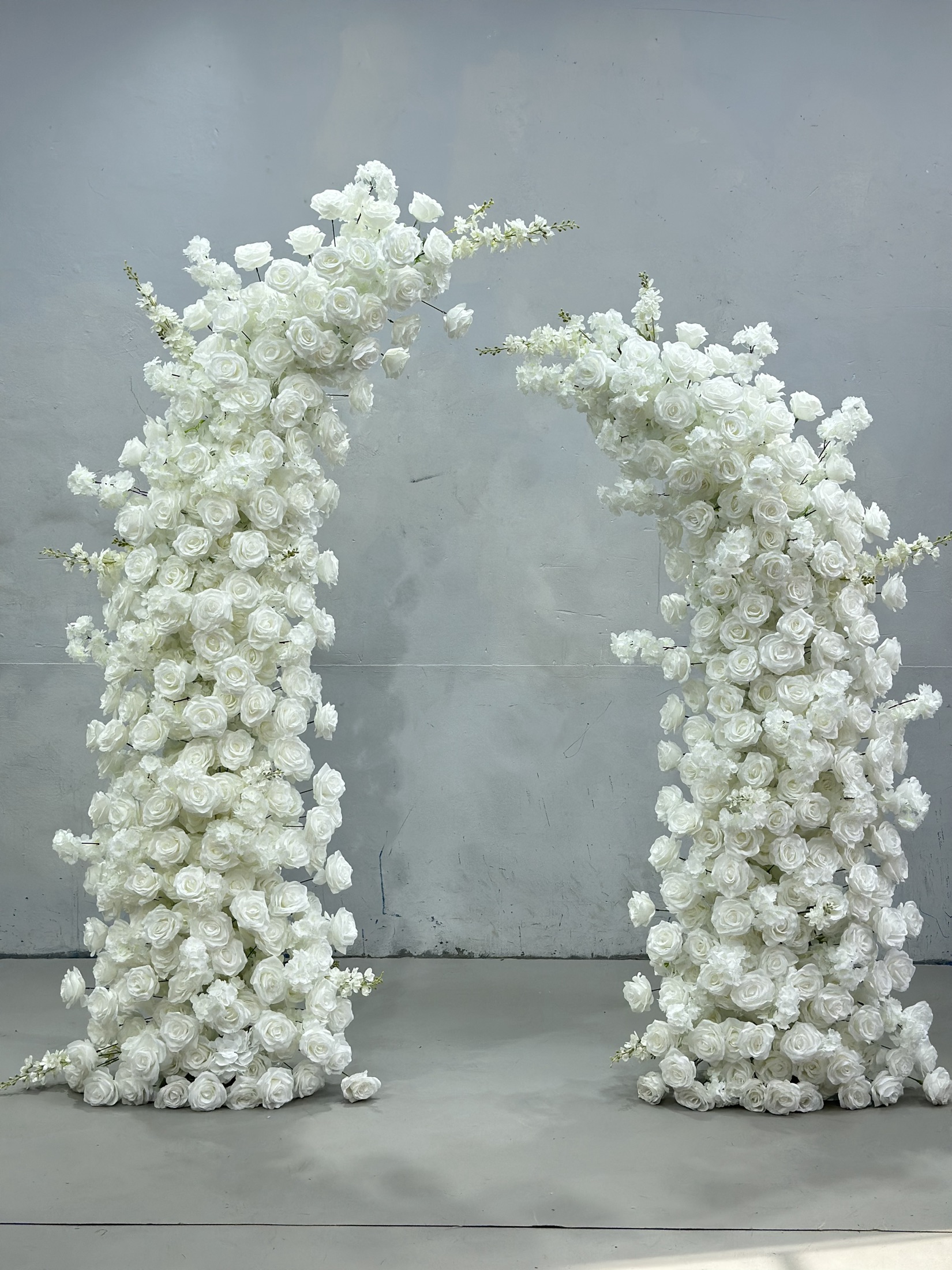 U-shaped faux-flower arch made with white roses and blossoms
