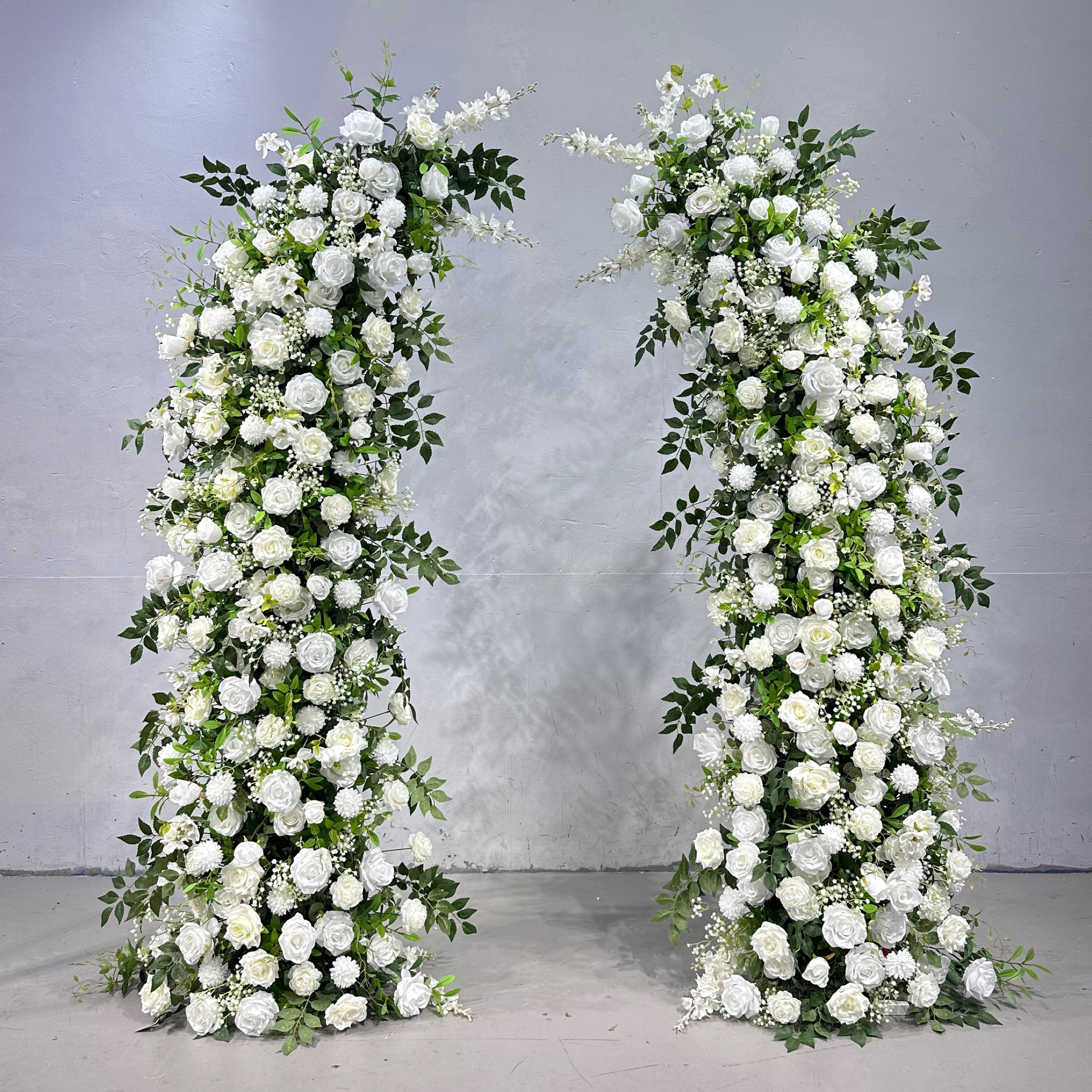 Horn-shaped faux-flower arch with ivory roses, white blooms and green leaves