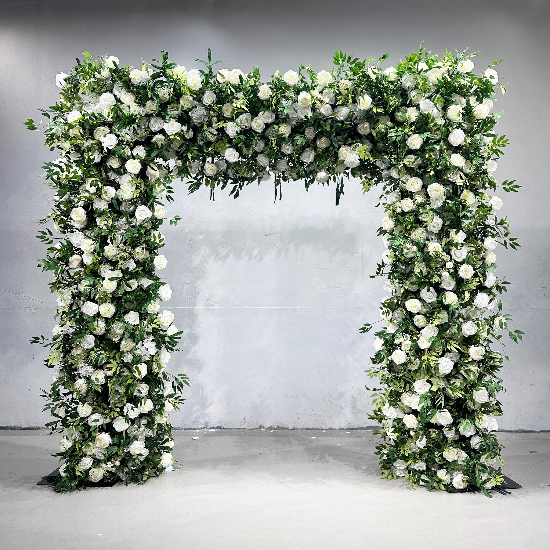 Square faux-flower arch with ivory roses and abundant green foliage