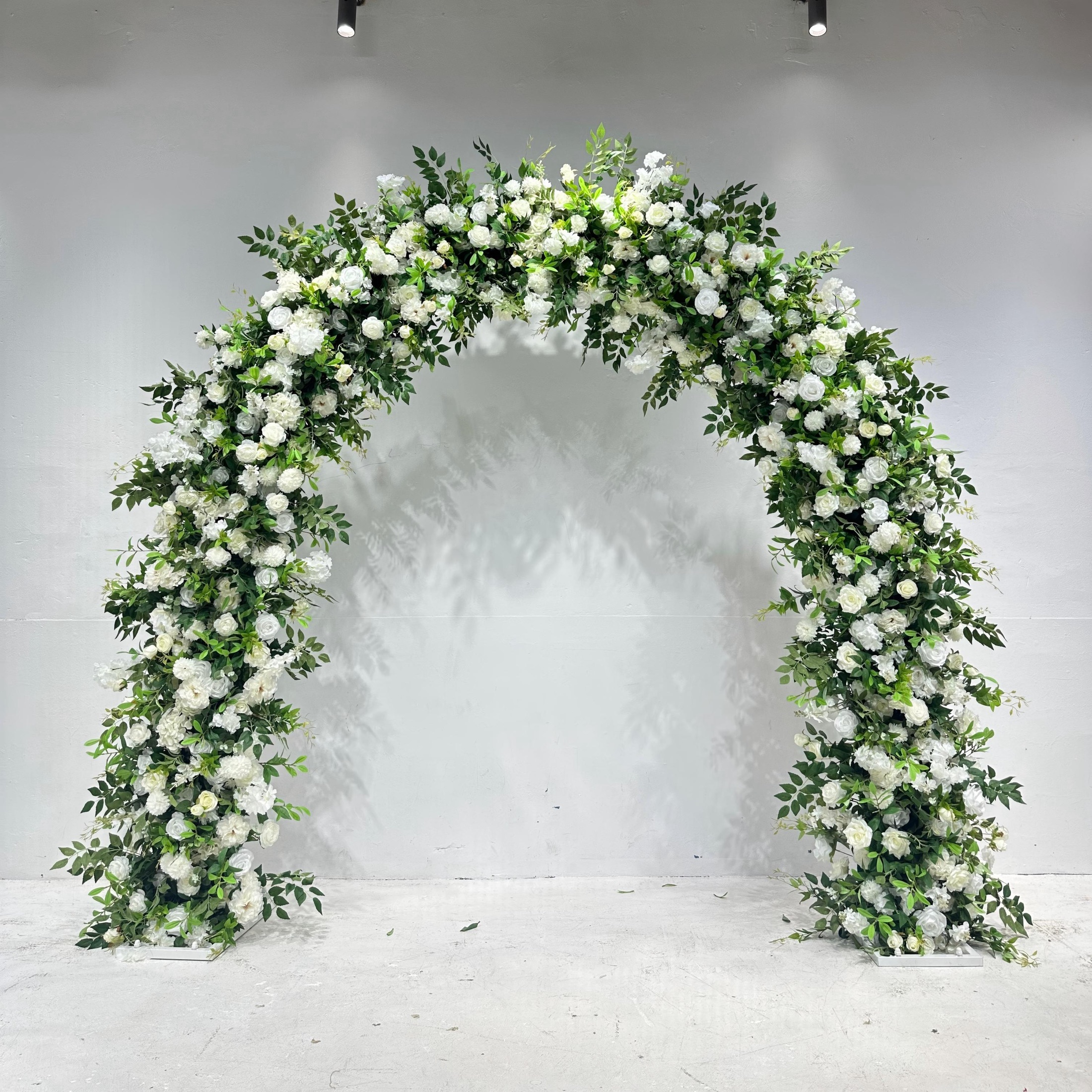 Wide U-shaped faux-flower arch with ivory flowers and layered greenery