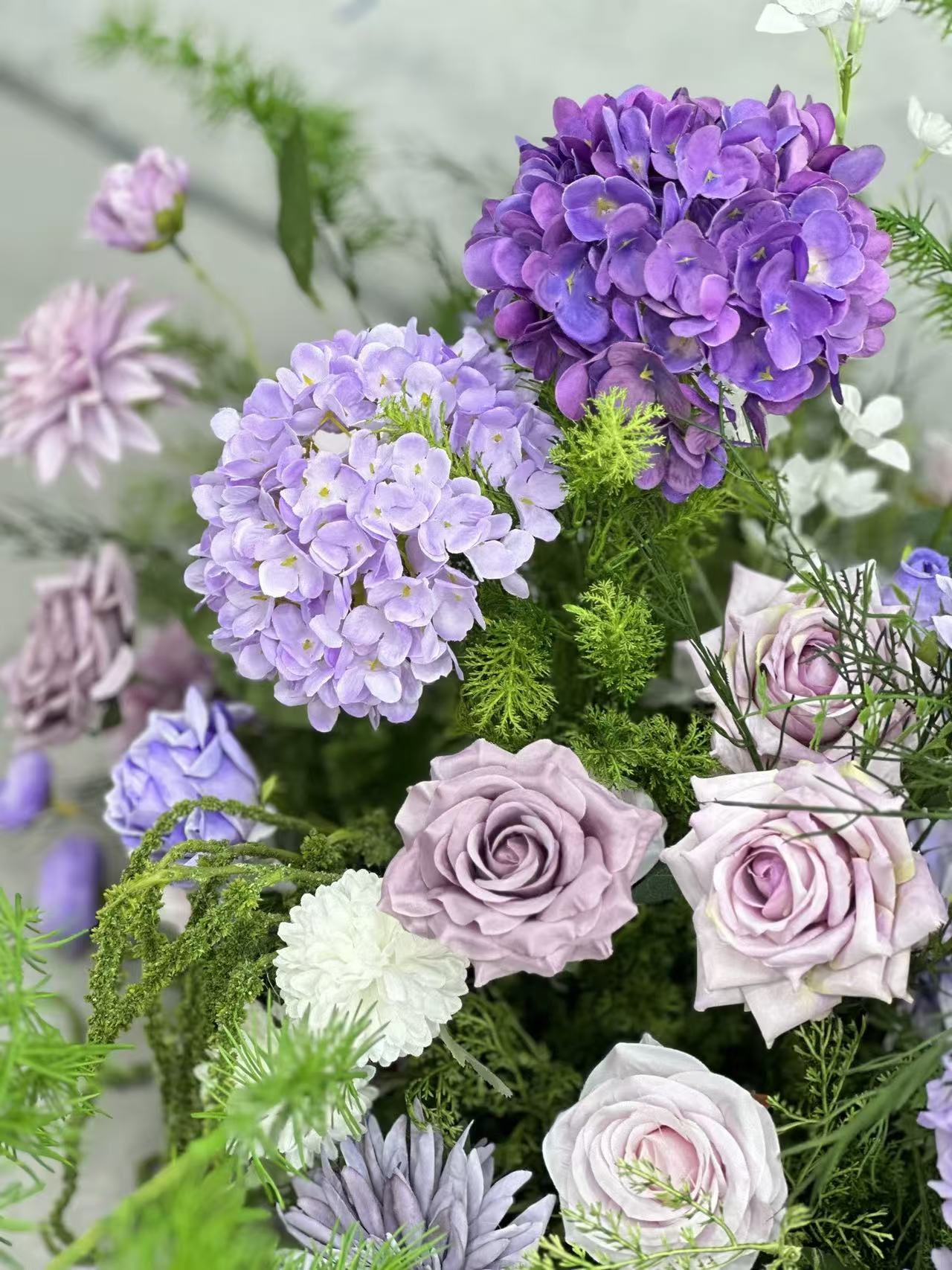 Close view of purple hydrangeas, mauve roses and white blooms